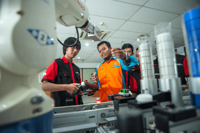 Students study a robotic arm in a school in Indonesia. 