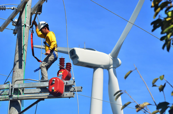 A man fixing a wind turbine in the Philippines.