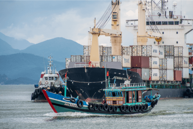 A tugboat sails near a container ship.