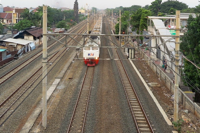 A railway train  zooms past houses in Indonesia