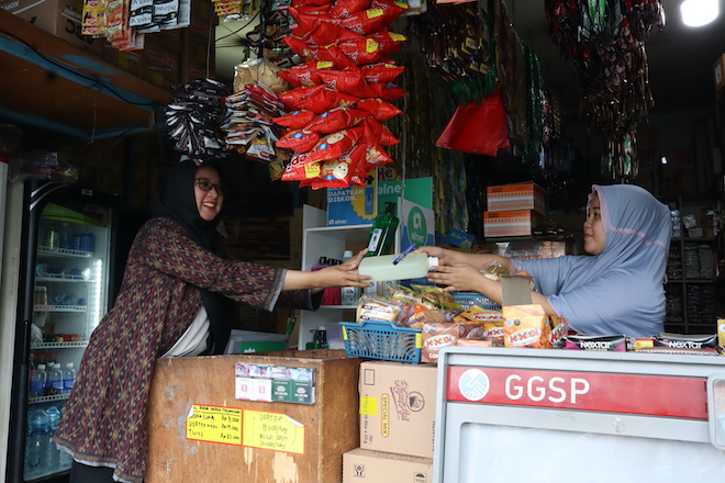 An Alner customer buying her daily necessities in reusable container from a convenience store in Indonesia.