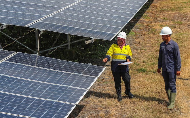 Workers in a solar farm in Indonesia inspect solar panels.