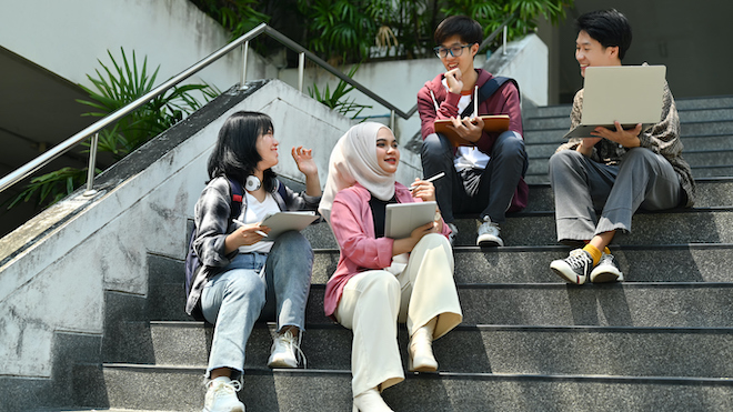 Students chatting on the steps of a university building. 