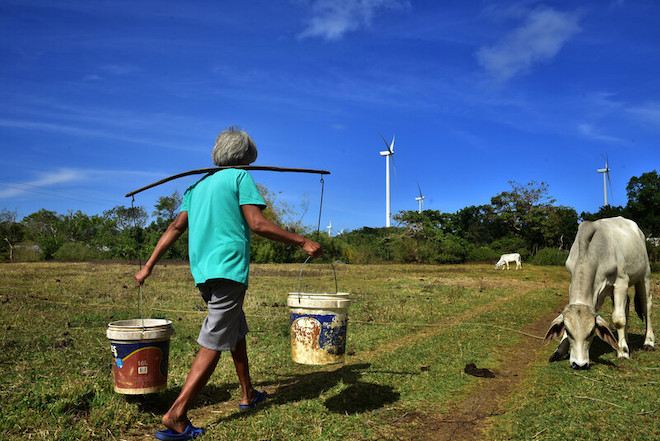 A  woman fetching water with the Bangui wind farm seen in the background.