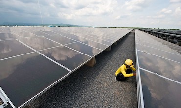 A man inspecting solar panels in a solar farm in Thailand.
