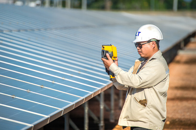A worker checking solar panels at a solar farm in Thailand.