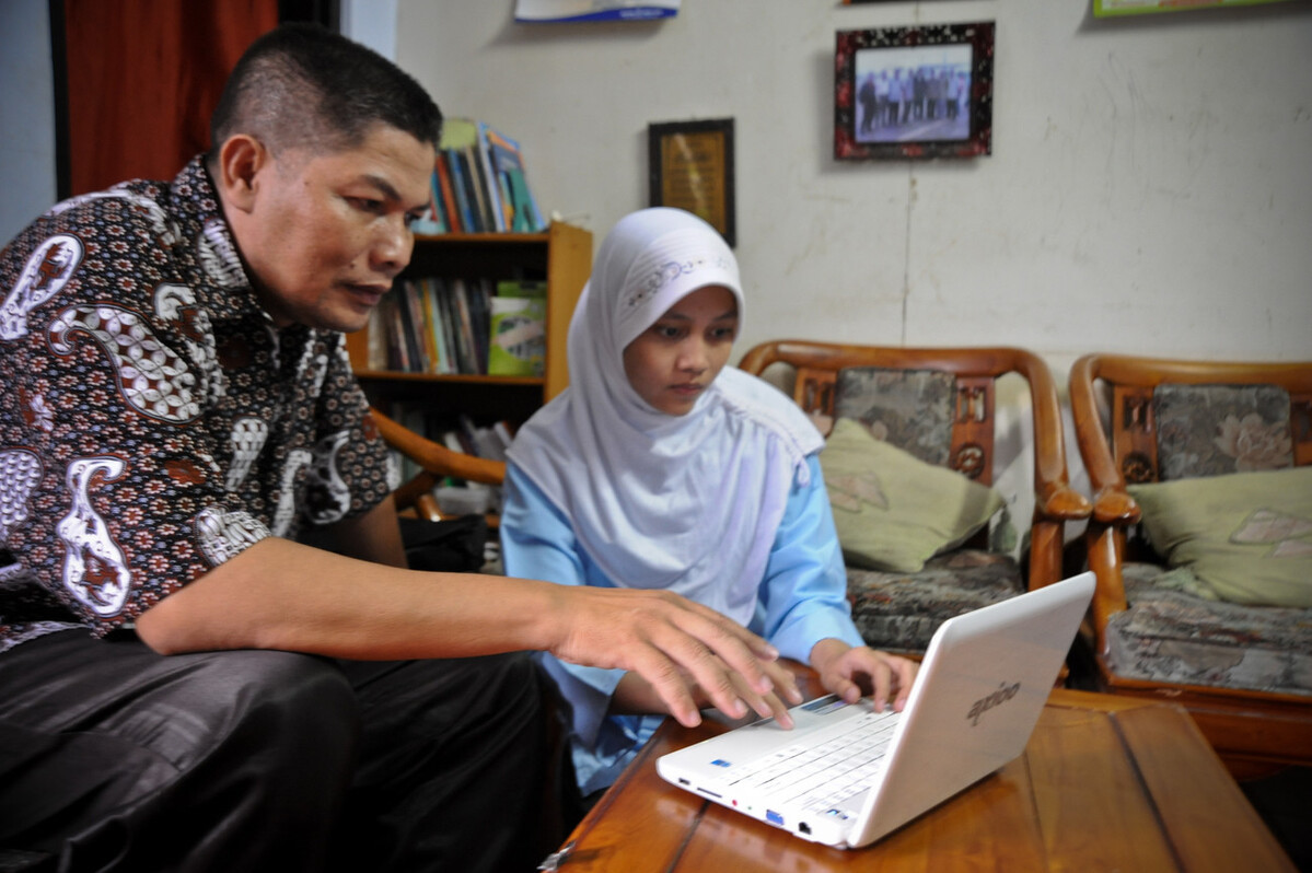 A student and her father using a laptop in Indonesia.