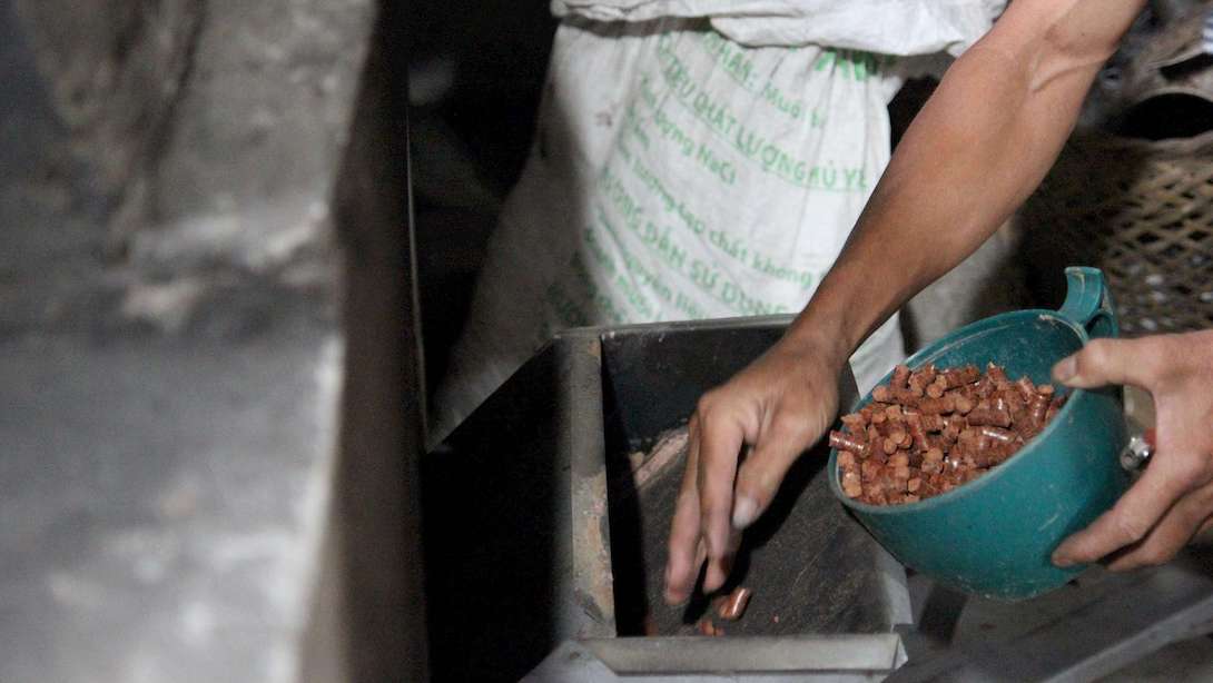 A man feeding raw materials into the VCBG stove.