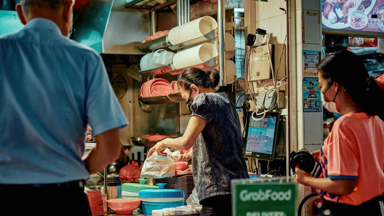 A vendor at a GrabFood merchant serves up food for customers. 