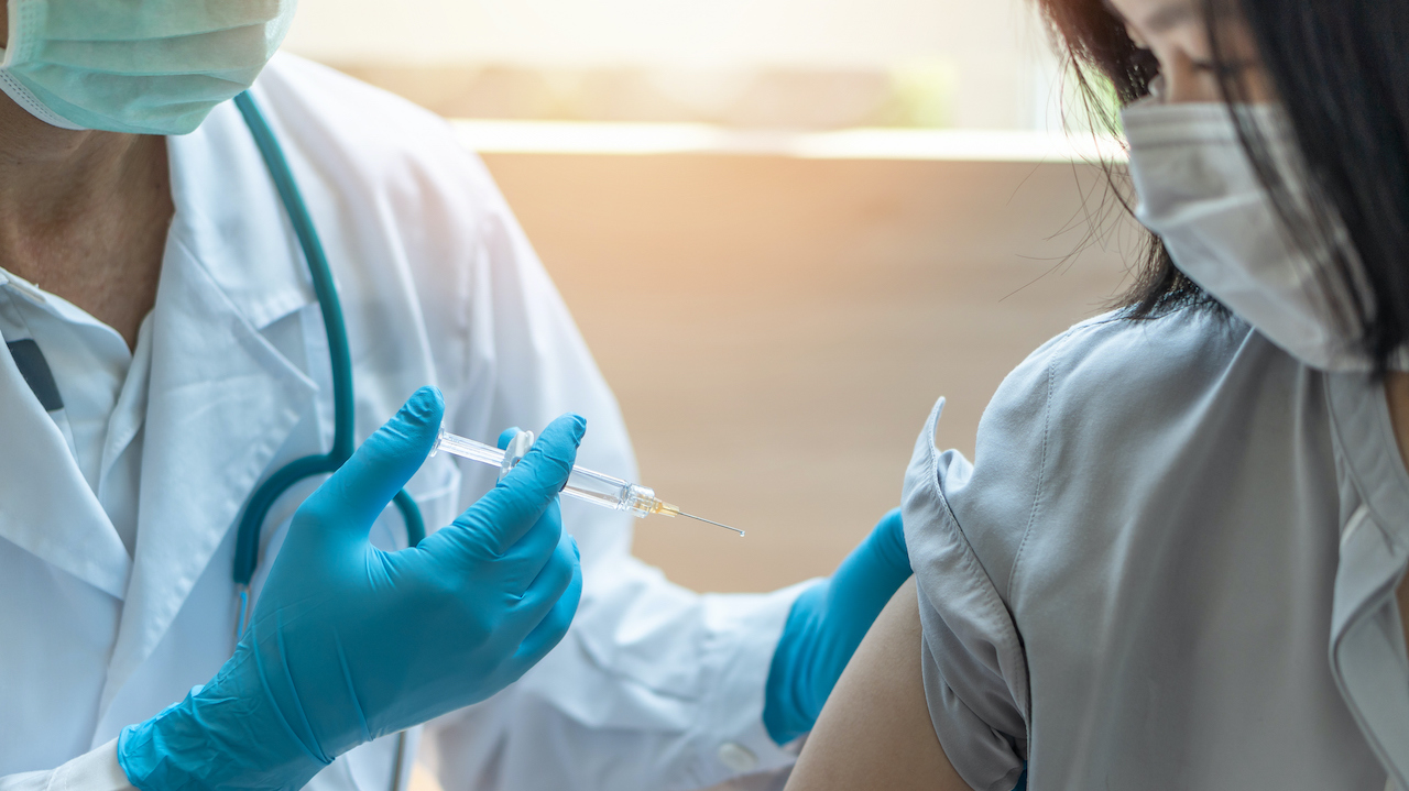 A woman getting a jab from a medical professional.