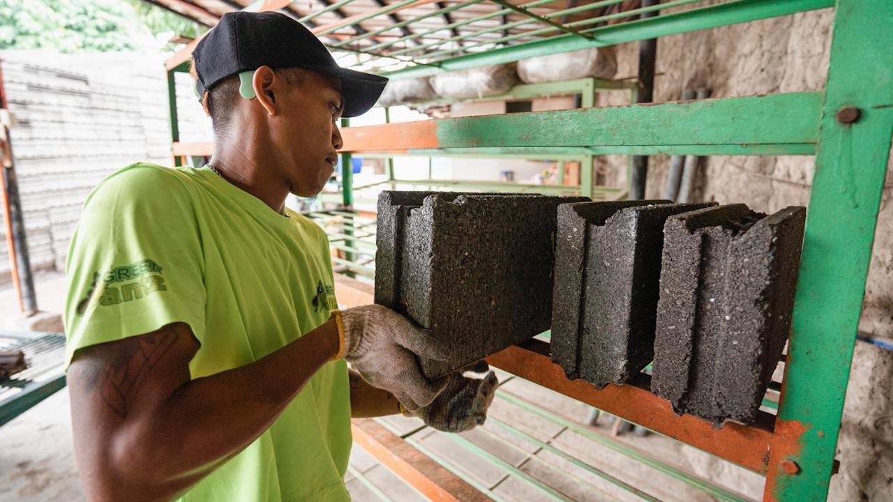 A worker stacking eco-bricks made from recycled plastics. Photo courtesy of Habitat for Humanity.