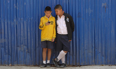 Schoolkids access a smartphone while waiting for classes to start in Thailand. 