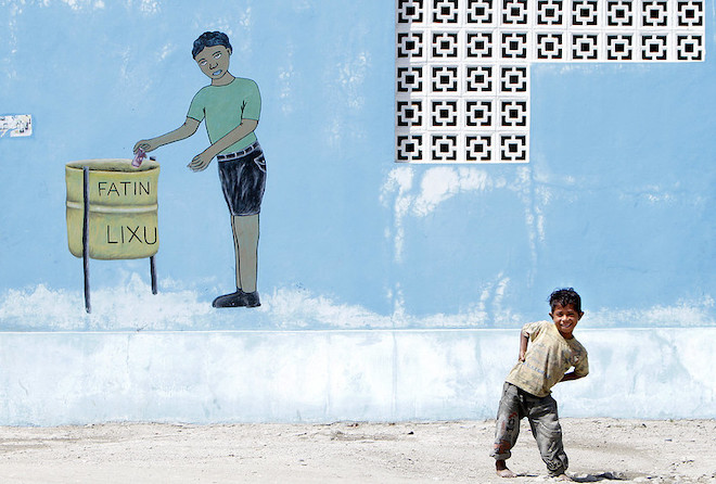 A boy posing in front of a mural.