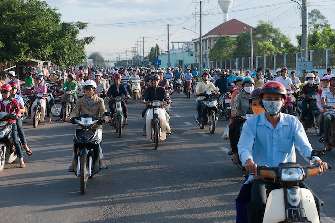 People riding their motorcycles on a street in Viet Nam.