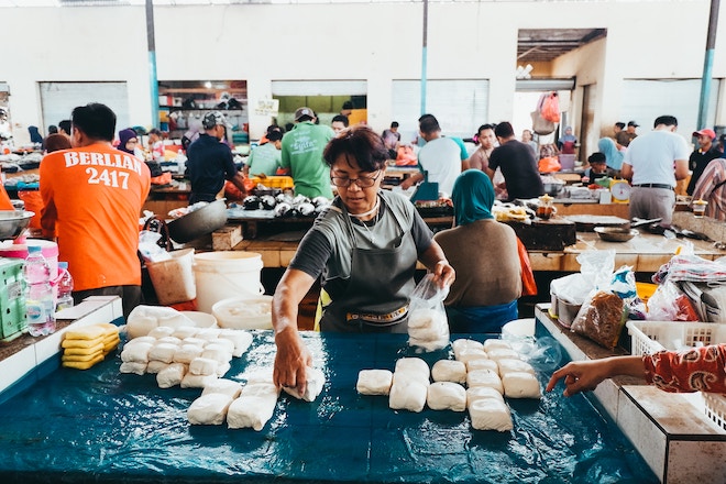 A business owner tends to her goods at a wet market.