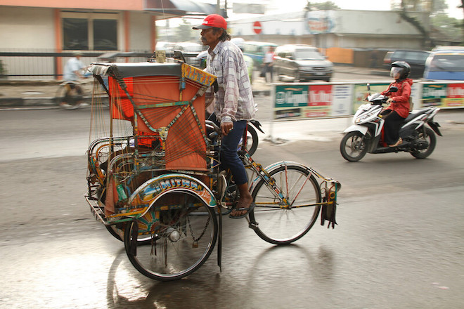 A becak ferries passengers down the roads of Bandung. A becak is a traditional form of transportation in Indonesia.