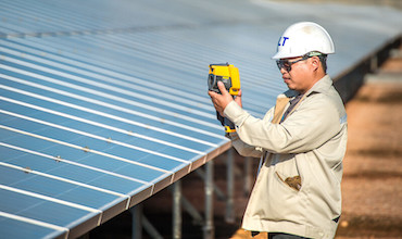 A worker checking solar panels at a solar farm in Thailand.