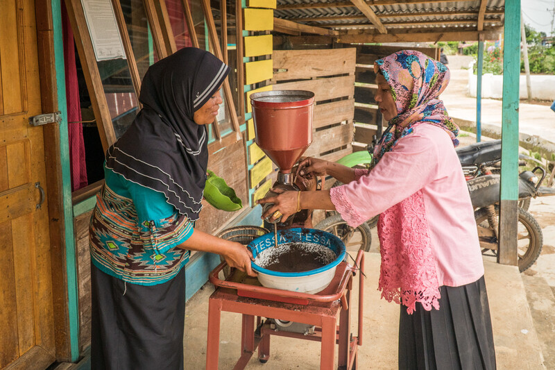 Women grinding coffee in Indonesia.