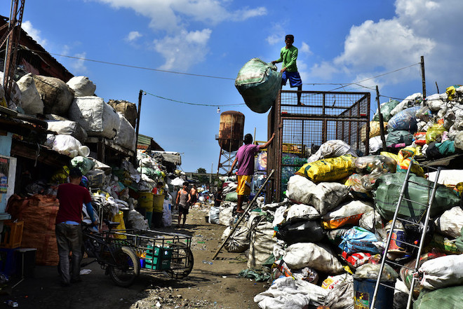Workers sort trash at a landfill.