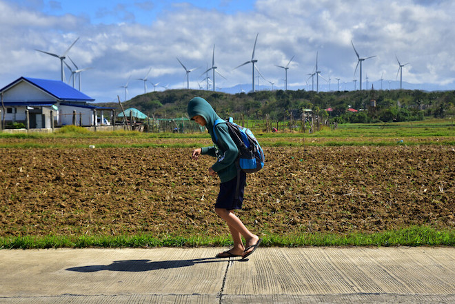 A student walks past a newly prepared field near the Burgos Wind Farm in Ilocos Norte, Philippines.