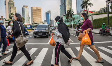 People wearing masks crossing the street in Indonesia.