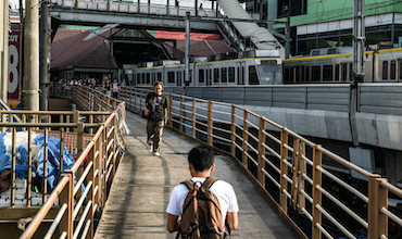 Commuters navigate the walkway connecting railway lines in EDSA, Philippines. 