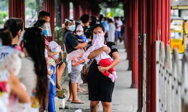Women carrying children queueing for their regular vaccination in the Philippines.