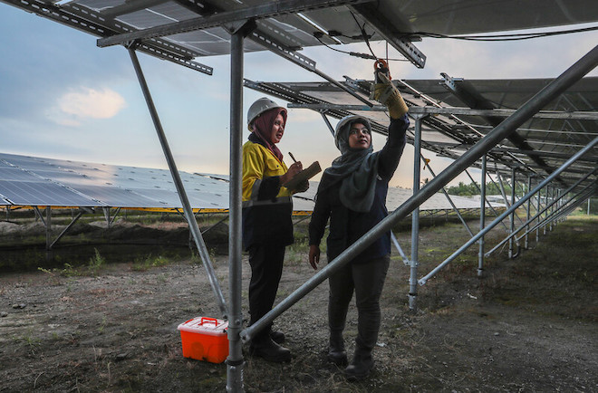 Employees at a solar farm in Indonesia doing maintenance work.