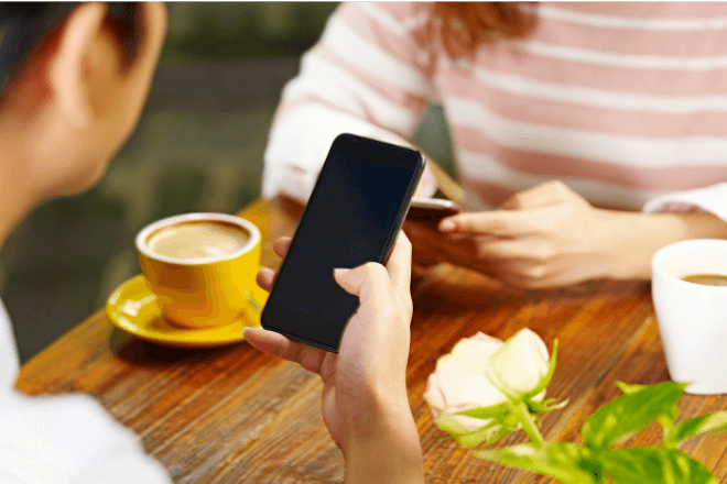 Two people having coffee while using their smartphones.