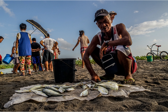 A fisherman selling some of his fish harvest.