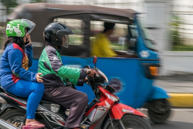A man driving a motorcycle with a passenger.