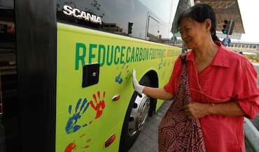 A woman stamps her hand print onto a hybrid bus.