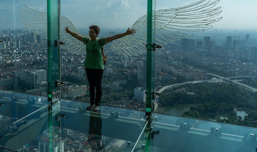 A tourist posing in front of an image of wings in an observation deck in Hanoi.