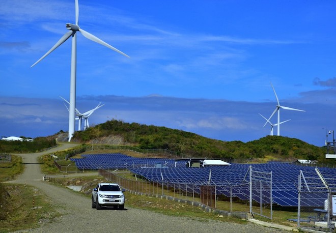 A vehicle passing by a solar and wind farm in the Philippines.