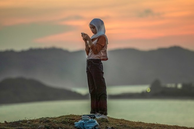 A woman looks at her phone while sightseeing in Indonesia.