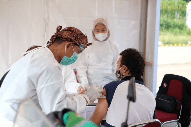 Health workers assist a patient during a vaccine drive.