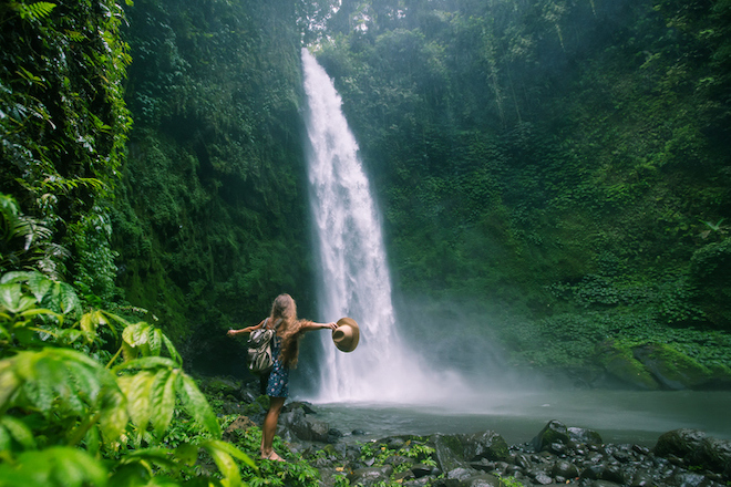 A tourists looking at the Nungnung waterfall in Bali, Indonesia.