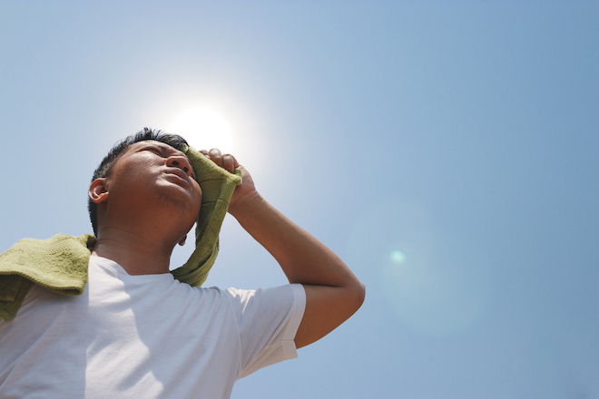 A man wiping sweat off his face during a hot day.