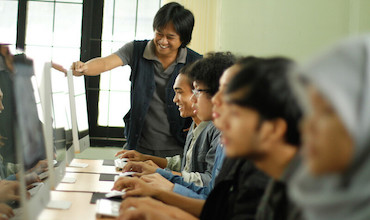 A teacher instructs students during a computer class in Indonesia.
