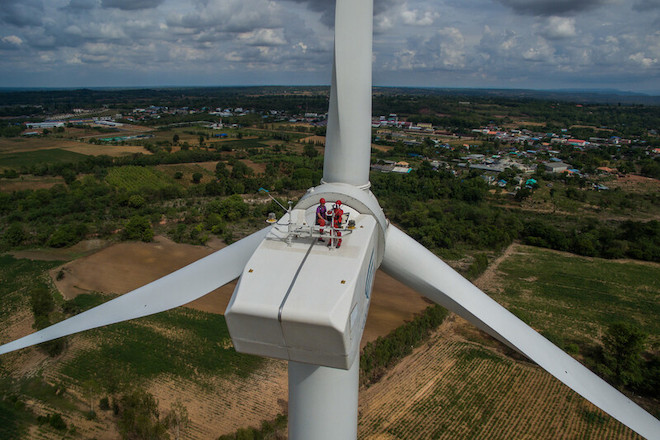 Two men doing maintenance work on a wind turbine in Thailand.