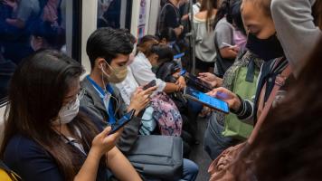 Commuters using their mobile phones on the Skytrain in Bangkok. Photo credit: ADB.