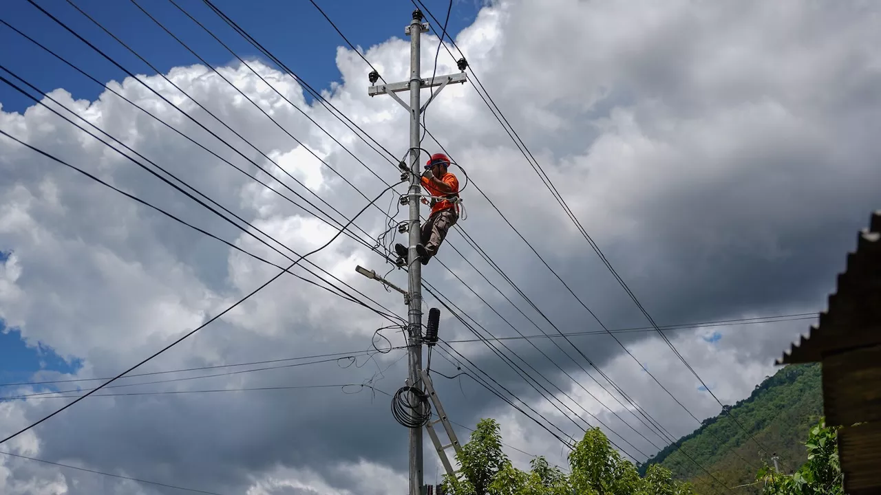 A lineman climbs up a transmission pole. Photo credit: ADB.
