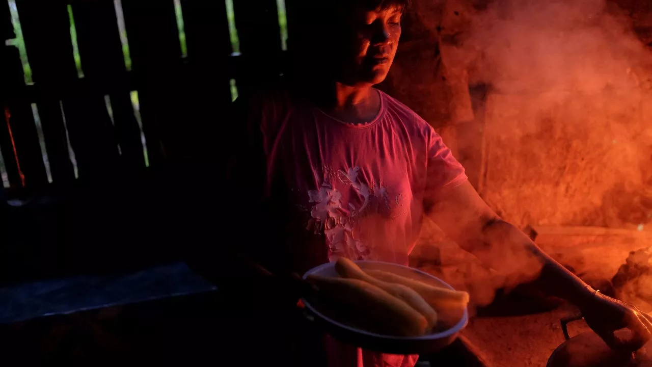 Smoke envelops a woman as she cooks over open fire. Photo credit: ADB.
