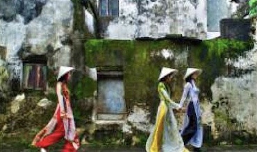 Women wearing traditional dress explore a tourist site in Viet Nam.